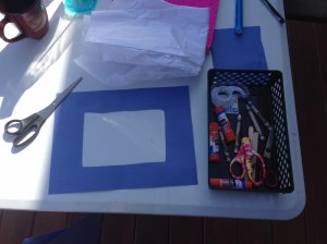 Gather your supplies and cut out a square in each blue construction paper that will be used.